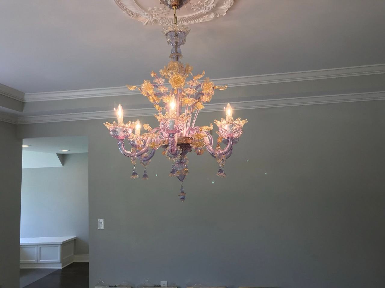 A multi-arm glass chandelier hung on a ceiling medallion