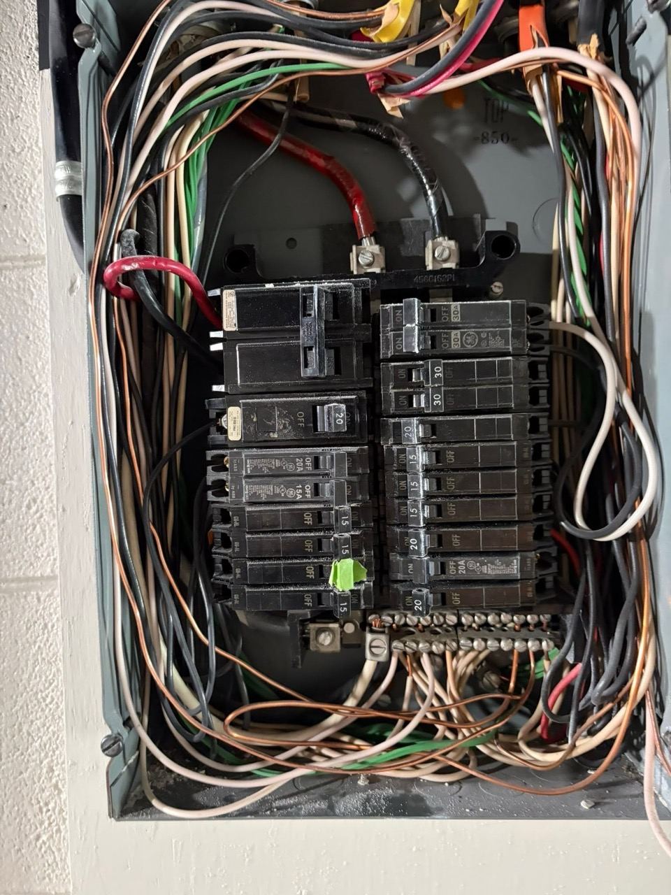 The inside of a crowded older panel, circuits traced and re-terminated